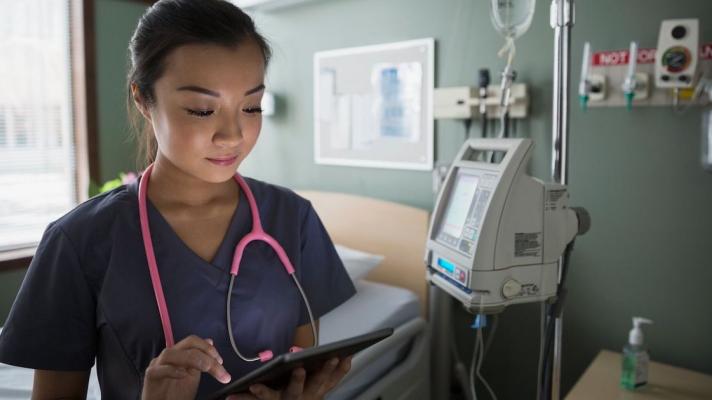 A nurse looking at a digital tablet
